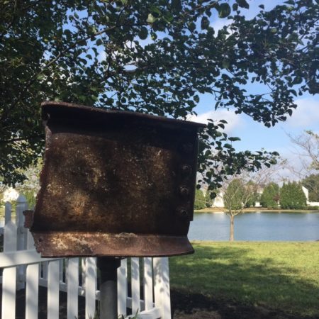 A piece a charred and bent steel mounted a pole with a lake in background